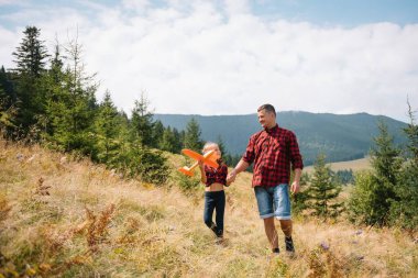 Mutlu baba ve küçük çocuk dağlarda yürüyorlar. Babalar Günü. Ulusal parkta tatil