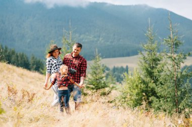 Ormanda dinlenen çocuklu genç bir aile.