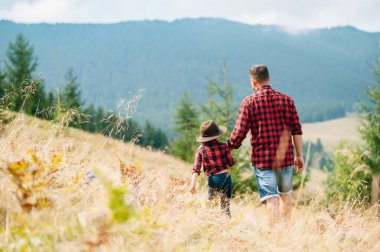 Mutlu baba ve küçük çocuk dağlarda yürüyorlar. Babalar Günü. Ulusal parkta tatil
