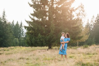 Anne ve oğlu dağlarda dinleniyorlar. Bir dağda dinlenen çocuklu genç bir aile. Ulusal parkta tatil