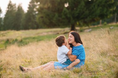 Anne ve oğlu dağlarda dinleniyorlar. Bir dağda dinlenen çocuklu genç bir aile. Ulusal parkta tatil