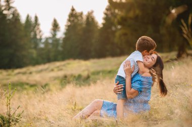 Anne ve oğlu dağlarda dinleniyorlar. Bir dağda dinlenen çocuklu genç bir aile. Ulusal parkta tatil