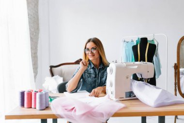 Yeni koleksiyon üzerinde çalışıyorum. Yeni düzen. Kadın moda tasarımcısı atölyedeki yeni kıyafetler üzerinde çalışıyor..