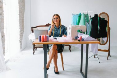 Yeni koleksiyon üzerinde çalışıyorum. Yeni düzen. Kadın moda tasarımcısı atölyedeki yeni kıyafetler üzerinde çalışıyor..