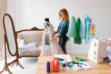 Yeni koleksiyon üzerinde çalışıyorum. Yeni düzen. Kadın moda tasarımcısı atölyedeki yeni kıyafetler üzerinde çalışıyor..