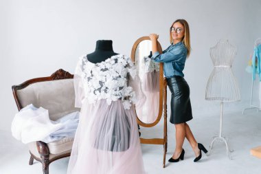 Yeni koleksiyon üzerinde çalışıyorum. Yeni düzen. Kadın moda tasarımcısı atölyedeki yeni kıyafetler üzerinde çalışıyor..