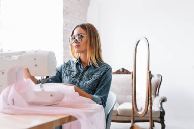 Çekici bayan moda tasarımcısı atölyesinde çalışıyor. Yeni kıyafet koleksiyonu yapan şık bir kadın..