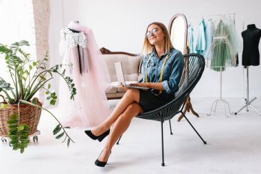 Çekici bayan moda tasarımcısı atölyesinde çalışıyor. Yeni kıyafet koleksiyonu yapan şık bir kadın..