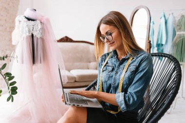 Çekici bayan moda tasarımcısı atölyesinde çalışıyor. Yeni kıyafet koleksiyonu yapan şık bir kadın..