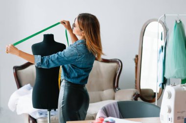 Yeni koleksiyon üzerinde çalışıyorum. Yeni düzen. Kadın moda tasarımcısı atölyedeki yeni kıyafetler üzerinde çalışıyor..