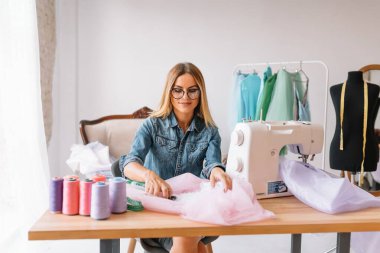 Yeni koleksiyon üzerinde çalışıyorum. Yeni düzen. Kadın moda tasarımcısı atölyedeki yeni kıyafetler üzerinde çalışıyor..