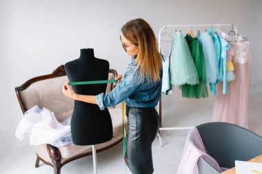 Yeni koleksiyon üzerinde çalışıyorum. Yeni düzen. Kadın moda tasarımcısı atölyedeki yeni kıyafetler üzerinde çalışıyor..