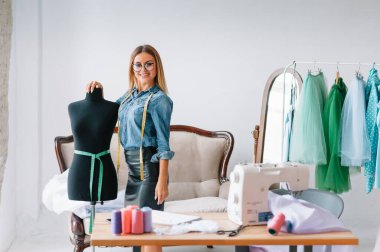 Herhangi bir hata yapamam. Kadın moda tasarımcısı atölyedeki yeni kıyafetler üzerinde çalışıyor..