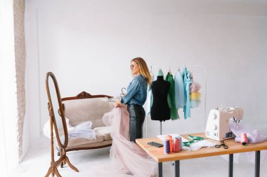 Yeni koleksiyon üzerinde çalışıyorum. Yeni düzen. Kadın moda tasarımcısı atölyedeki yeni kıyafetler üzerinde çalışıyor..