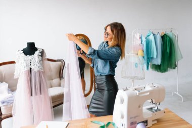 Yeni koleksiyon üzerinde çalışıyorum. Yeni düzen. Kadın moda tasarımcısı atölyedeki yeni kıyafetler üzerinde çalışıyor..