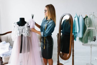 Yeni koleksiyon üzerinde çalışıyorum. Yeni düzen. Kadın moda tasarımcısı atölyedeki yeni kıyafetler üzerinde çalışıyor..