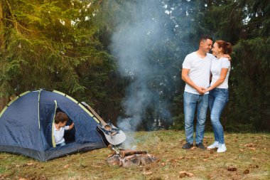 Dışarıda kamp yapan ve çadırda oturan romantik bir çift. Mutlu adam ve kadın romantik bir kamp tatilindeler..