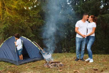 Dışarıda kamp yapan ve çadırda oturan romantik bir çift. Mutlu adam ve kadın romantik bir kamp tatilindeler..