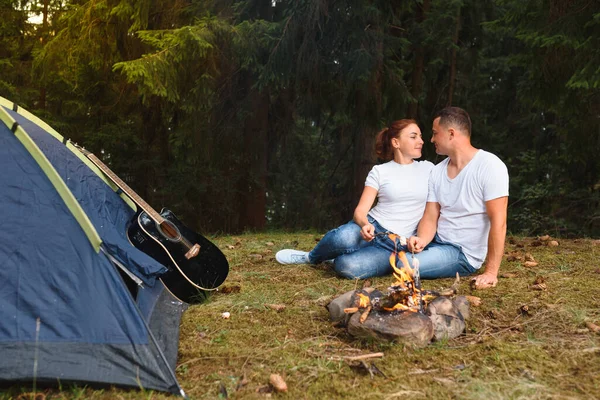 Romantic couple camping outdoors and sitting in a tent. Happy Man and woman on a romantic camping vacation.