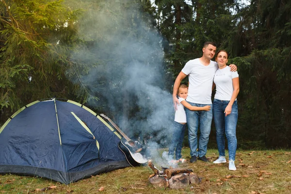 Dışarıda kamp yapan ve çadırda oturan romantik bir çift. Mutlu adam ve kadın romantik bir kamp tatilindeler..