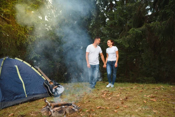 Romantic couple camping outdoors and sitting in a tent. Happy Man and woman on a romantic camping vacation.