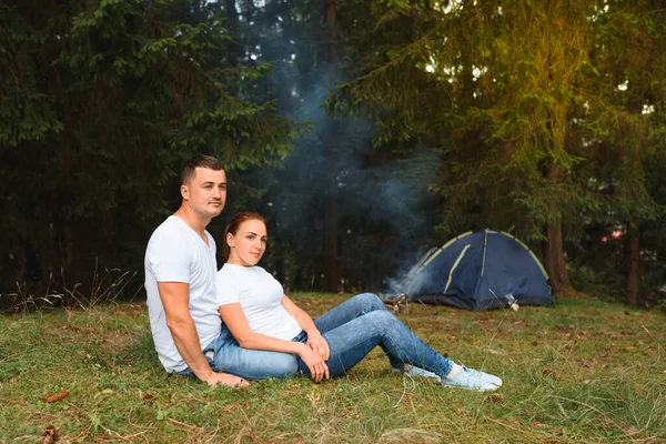 Romantic couple camping outdoors and sitting in a tent. Happy Man and woman on a romantic camping vacation.