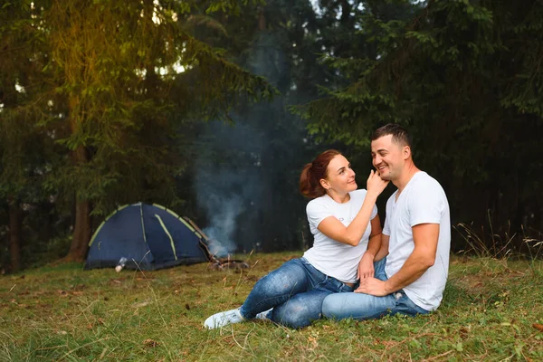 Romantic couple camping outdoors and sitting in a tent. Happy Man and woman on a romantic camping vacation.