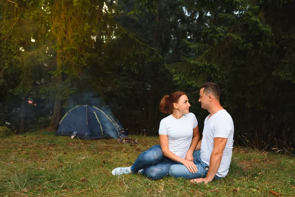 Romantic couple camping outdoors and sitting in a tent. Happy Man and woman on a romantic camping vacation.