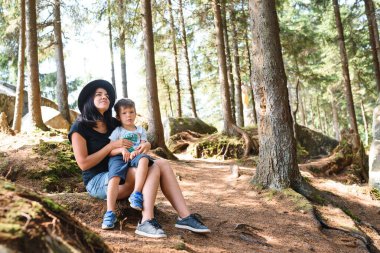 Genç anne ve küçük oğlu seyahat ediyorlar. Aile gezisi dağlarda. Ulusal Park. Çocuklarla yürüyüş. Aktif yaz tatili. Fisheye merceği