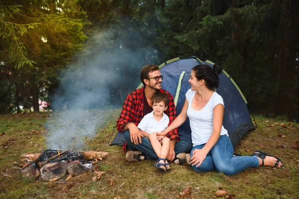 Family camping and cooking in campfire