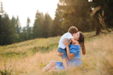 Yeşil parktaki yeşil çimlerin üzerinde oturan kitabı olan anne ve oğlu. Mutlu aile ilişkileri ve kaygısız boş zaman kavramı