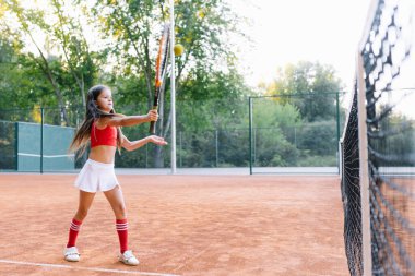 Sıcak ve güneşli bir yaz gününde dışarıda badminton oynayan tatlı küçük kız.