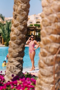 Yaz tatilinde havuzda yüzen güzel bir kadın, seksi kız bikini, bronzlaşmış kadın modeli, kumsalda eğlenen bir kız, lüks bir yaşam tarzı.