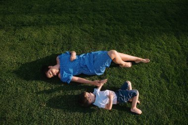 Şık bir anne ve yakışıklı bir oğul yeşil çimlerde eğleniyor. Mutlu aile kavramı. Aile hayatı olan güzel doğa manzarası. Mutlu bir aile birlikte dinleniyor. Anneler Günü