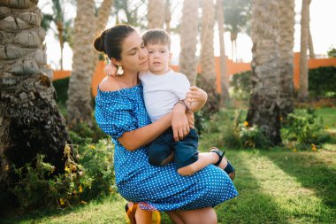 Şık bir anne ve yakışıklı bir oğul yeşil çimlerde eğleniyor. Mutlu aile kavramı. Aile hayatı olan güzel doğa manzarası. Mutlu bir aile birlikte dinleniyor. Anneler Günü