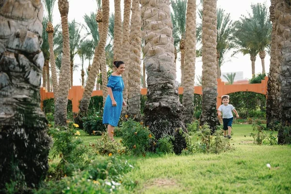 时髦的母亲和英俊的儿子在绿色的草坪上玩得很开心 快乐的家庭观念 美丽的自然景观与家庭户外生活方式 幸福的家人在一起休息母亲节 — 图库照片