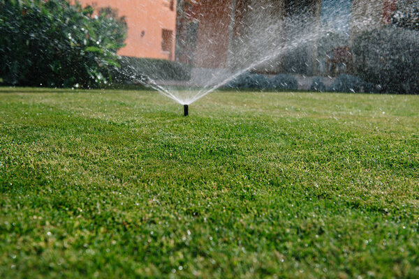 Modern device of irrigation garden. Irrigation system - technique of watering in the garden. Lawn sprinkler spraying water over green grass.