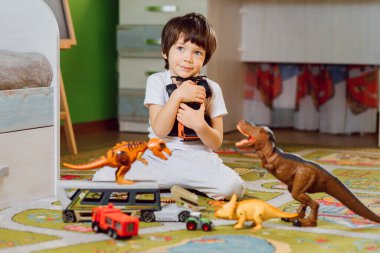 İçeride oyuncak arabalarla oynayan sevimli küçük bir çocuk. Anaokulu çocuğu evde ya da kreşte eğleniyor. Farklı araçlardan oluşan büyük bir koleksiyon. Mutluluk oyunu.