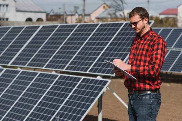 Engineer. Man near solar panel. Worker with a folder.