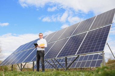 Güneş panelleri ve mavi gökyüzü. Güneş panellerinin yanında duran adam. Güneş paneli güneşten yeşil, çevre dostu enerji üretir.