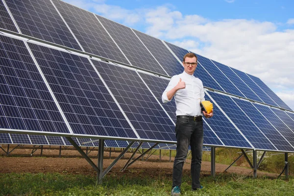 Solar energy. Young business man in a white shirt near the solar panels to power plants.