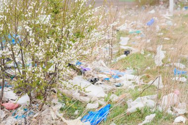 Doğanın ekolojik kirliliği. Plastik torba, bitkilerin arasına dağların arka planına dolanmış. Küresel çevre kirliliği. Geri dönüşüm, plastikten arta kalan toprakları temizlemek..