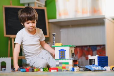 Karantina sırasında evde tek başına renkli yapı taşları oynayan üzgün, düşünceli bir çocuk. geliştirme oyunu. Kendini soyutlama döneminde yalnızlık