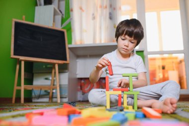 Karantina sırasında evde tek başına renkli yapı taşları oynayan üzgün, düşünceli bir çocuk. geliştirme oyunu. Kendini soyutlama döneminde yalnızlık