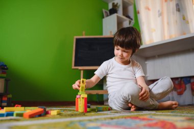 Karantina sırasında evde tek başına renkli yapı taşları oynayan üzgün, düşünceli bir çocuk. geliştirme oyunu. Kendini soyutlama döneminde yalnızlık