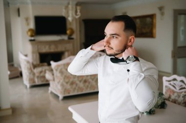 Saygıdeğer genç bir adam klasik iç mimarisi olan bir odada duruyor. Lüks. Erkek güzelliği, moda.