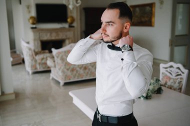 Saygıdeğer genç bir adam klasik iç mimarisi olan bir odada duruyor. Lüks. Erkek güzelliği, moda.