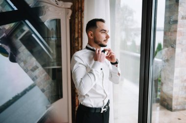 Saygıdeğer genç bir adam klasik iç mimarisi olan bir odada duruyor. Lüks. Erkek güzelliği, moda.