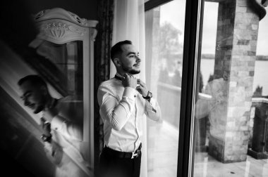 Saygıdeğer genç bir adam klasik iç mimarisi olan bir odada duruyor. Lüks. Erkek güzelliği, moda.