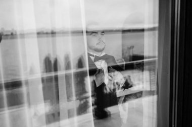 Saygıdeğer genç bir adam klasik iç mimarisi olan bir odada duruyor. Lüks. Erkek güzelliği, moda.